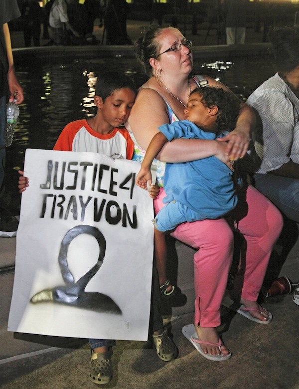 In this Saturday, July 13, 2013 file photo, a mother holds and sits with her children after hearing the verdict of not guilty in the trial of neighborhood watch volunteer George Zimmerman at the Seminole County Courthouse, in Sanford, Fla. Zimmerman was cleared of all charges Saturday in the shooting of unarmed teenager Trayvon Martin, whose killing unleashed furious debate across the U.S. over racial profiling, self-defense and equal justice. Some view Zimmerman's acquittal as a blow to race relations. (AP Photo/Mike Brown, File)