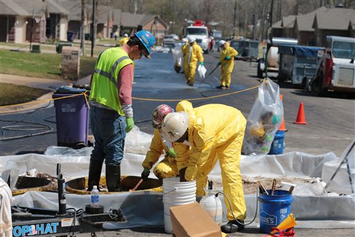 A crew member with Exxon Mobil washes oil from another crew member's boots in a subdivision in Mayflower, Ark., in this April 1, 2013. photo. The leak dumped about 210,000 gallons of heavy oil into the neighborhood.