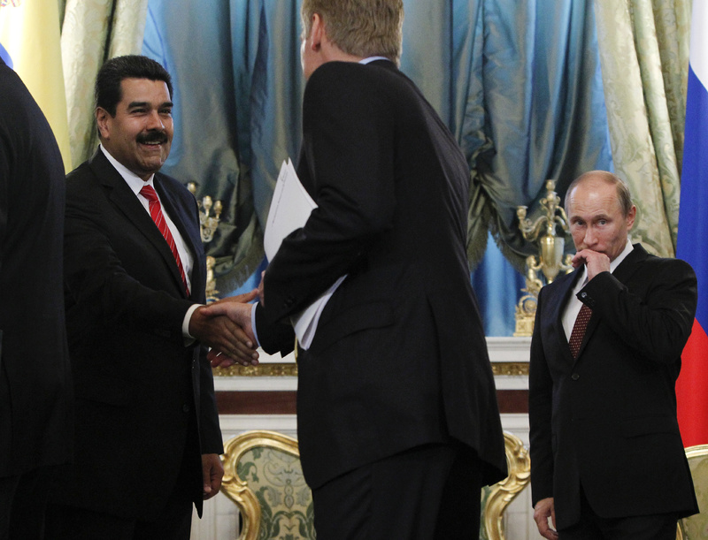 Venezuelan President Nicolas Maduro, left, shakes hands with Russian presidential spokesman Dmitry Peskov on Tuesday during a meeting at the Kremlin in Moscow. At right is Russia's President Vladimir Putin. Maduro has expressed support for Edward Snowden.