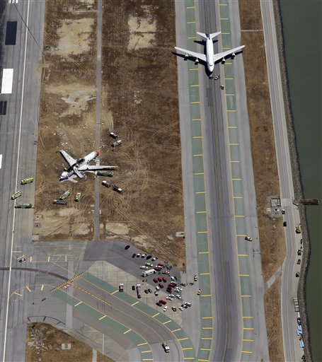 This aerial photo shows a United Airlines plane sitting on the adjacent runway next to the wreckage of the Asiana Flight 214 airplane after it crashed at the San Francisco International Airport in San Francisco, Saturday, July 6, 2013.