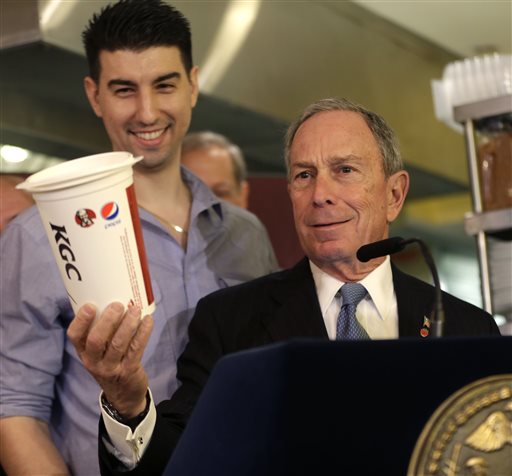 In this March 12, 2013, photo, New York City Mayor Michael Bloomberg looks at a 64-ounce cup, as Lucky's Cafe owner Greg Anagnostopoulos, left, stands behind him. An appeals court ruled Tuesday that New York City's Board of Health exceeded its legal authority and acted unconstitutionally when it tried to put a size limit on soft drinks served in city restaurants.