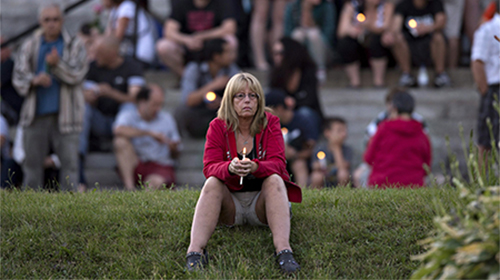 A women sits in front of the St-Agnes church during a vigil to the victims of the train crash in Lac-Megantic, Quebec, Friday, July 12, 2013. (AP Photo/The Canadian Press, Jacques Boissinot)