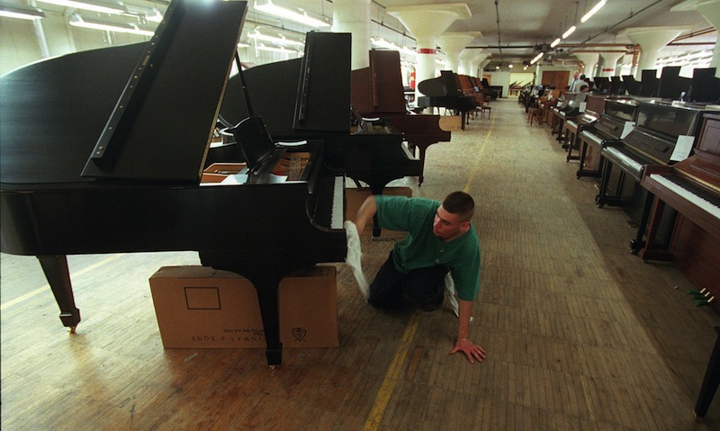 In a May 17, 1996 file photo, John Volastro, who works in the restoration department of Steinway and Sons, applies the finishing touches to a Steinway piano at piano maker's factory in the Queens Borough of New York. The famed piano maker Steinway is being acquired by private equity firm Kohlberg & Co. for about $438 million. Steinway, which has been in business for 160 years, said previously that was looking into selling the company. The board of the Waltham, Mass., company unanimously recommended Monday, July 1, 2013 that shareholders tender their stock. (AP Photo/Adam Nadel, File)