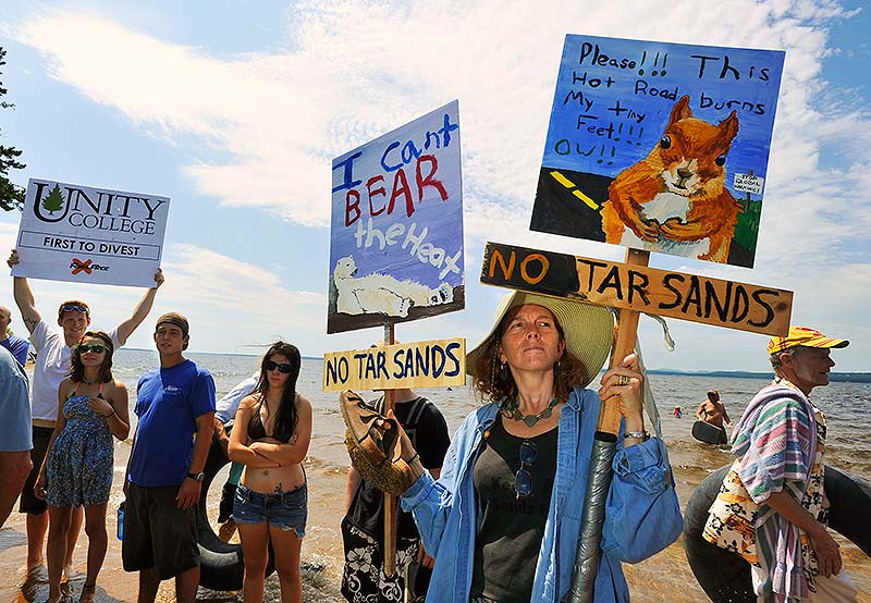 Members and supporters of the environmental advocate group 350.org held a rally at Sebago Lake State Park to protest the potential reversal of the Portland Pipeline that would transport tar-sands oil near Sebago Lake on Saturday. Lynn Stone, of Topsham, carries protest signs made by her niece and nephew at the rally.