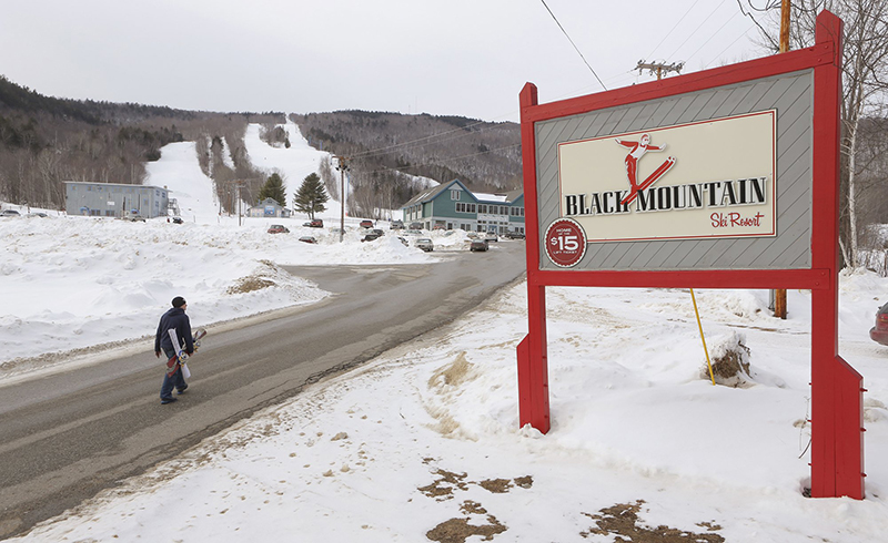 A snowboarder walks up the main access road to Black Mountain in Rumford in January.