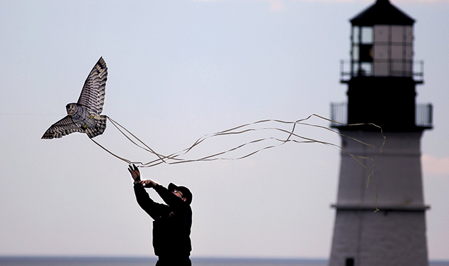 With Portland Head Light in the background, Tyler Romo, 19, of Yarmouth High School, launches a kite the shape of an owl at Fort Williams Park in Cape Elizabeth in this June 4, 2013 file photo. Proposed new rules would allow up to eight art vendors to sell their work at Fort Williams.