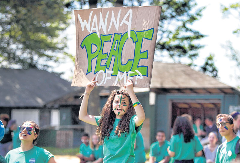 A camper displays a sign during a softball game at the Seeds of Peace camp in Otisfield on Friday.