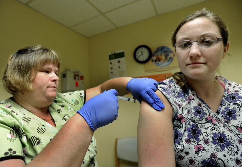 Susan Huff, a Portland Community Health Center medical assistant, administers a pertussis vaccine to colleague Brianna Gonthier. Adults should get a booster shot every 10 years.
