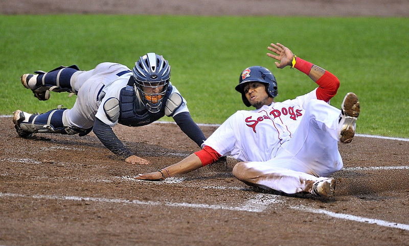 Michael Almanzar of the Portland Sea Dogs slides past Trenton catcher Francisco Arcia to score in the fourth inning of the first game of a doubleheader sweep Tuesday night.