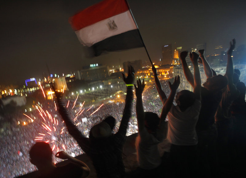 Fireworks go off in Cairo’s Tahrir Square as Egyptians wave a flag in celebration of the ouster of their first democratically elected president.