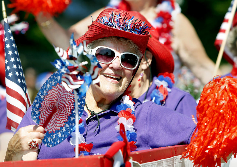 Janet Doherty of Old Orchard Beach waves to the crowd while riding on the Red Hat Society float during the 63rd Annual Independence Day Community Parade in Ocean Park.