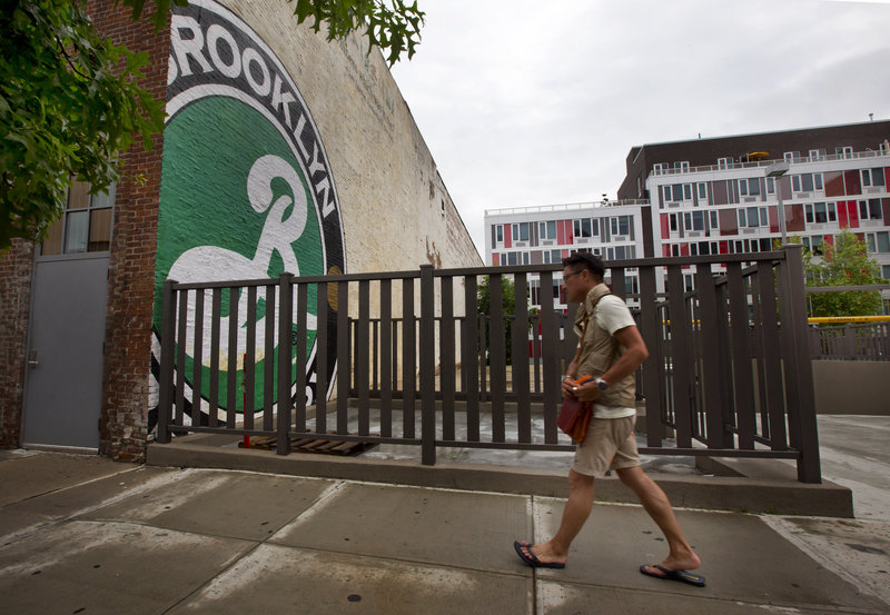 A modern apartment building stands in view of the Brooklyn Brewery, in Brooklyn, N.Y. The arrival of craft breweries can transform neighborhoods.