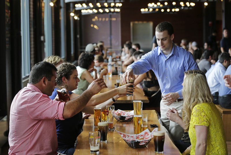 Customers sample a variety of beers at the Harpoon Brewery’s Beer Hall in the Seaport District of Boston. The area is now attracting upscale businesses.