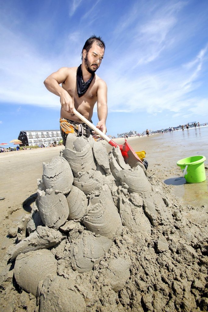 Mathieu Roy of Montreal works on a sand castle during a family vacation in Old Orchard Beach in 2012. A reader questions the two-year expiration date on a recent increase in Maine’s meals and lodging tax, saying that the total of such levies has never been a factor in her family’s vacation planning.