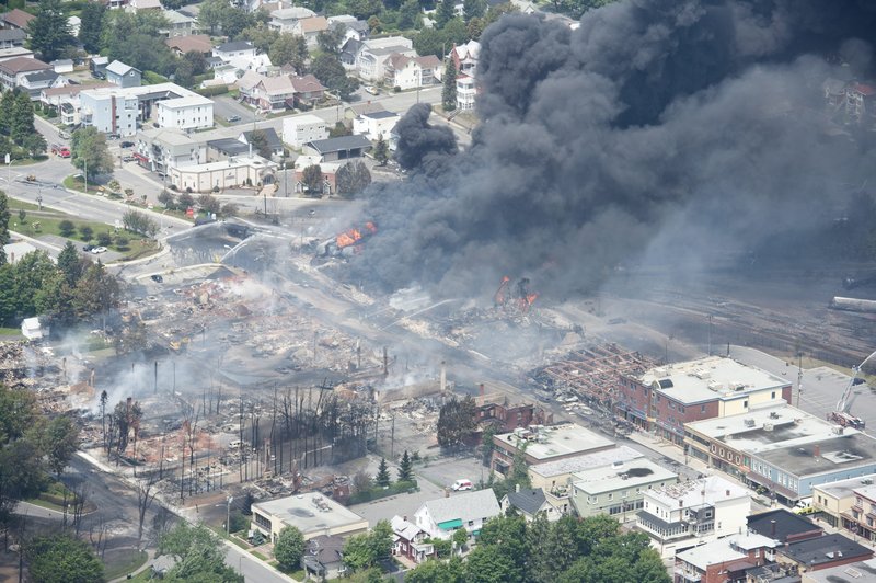 Smoke rises from railway cars that were carrying crude oil after derailing in downtown Lac Megantic, Quebec, Canada, Saturday, July 6, 2013. A large swath of Lac Megantic was destroyed Saturday after a train carrying crude oil derailed, sparking several explosions and forcing the evacuation of up to 1,000 people. (AP Photo/The Canadian Press, Paul Chiasson)