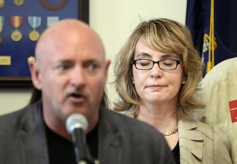 Former U.S. Rep. Gabrielle Giffords listens as her husband, Capt. Mark Kelly, describes the day Giffords was shot in 2011. The couple seek tougher gun-purchasing laws.