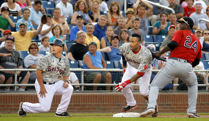 Sea Dogs base runner Tony Thomas looks toward the plate, along with Manager John Boles and New Britain third baseman Miguel Sano, to see if he can score after an errant throw. Thomas held at third but eventually scored on a passed ball.