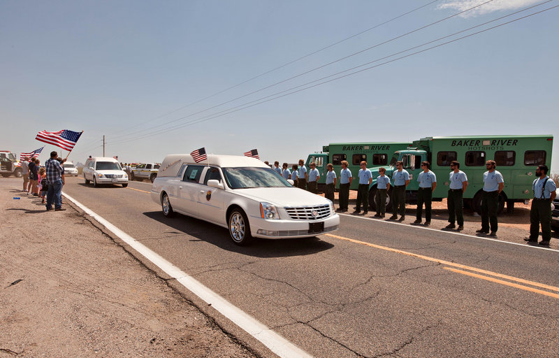 Hearses carrying the bodies of 19 Granite Mountain Hotshots move Sunday past Bureau of Land Management and U.S. Forest Service personnel on the way from Phoenix to Prescott, Ariz. A memorial service is set for Tuesday in Prescott, then funerals will be held for the men.