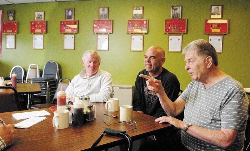 David Harville, left, Thomas “T.J.” Quinn, center, and Larry Day talk about the memorial wall display last week at Quinn’s restaurant, TJ’s Place, in Monmouth. There are seven plaques on the wall, one for each of the soldiers from the town killed in action in World War II.