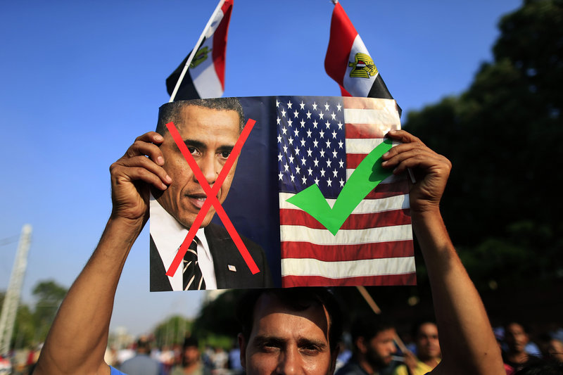 An opponent of Mohammed Morsi, Egypt’s recently deposed president, holds up a picture showing U.S. President Obama and the U.S. flag at a rally in Cairo, Egypt, on Sunday.