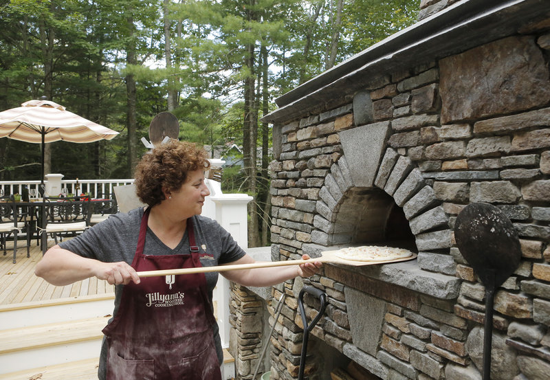 Instructor Jill Strauss shovels a Crabby Cheddar pizza into the oven, where the heat registered over 750 degrees, at Jillyanna’s Woodfired Cooking School in Kennebunkport.