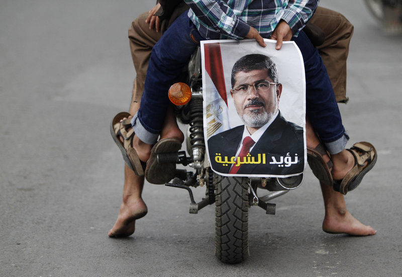 A pro-democracy protester holds a photo of deposed Egyptian President Mohamed Mursi while riding a motorcycle during a demonstration in Sanaa.