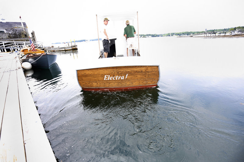 Eugene Story, owner of Maine Electric Boat Co., right, and Eric Graves, president of Boothbay Harbor Shipyard, leave the dock on their electric-powered lobster boat July 8 in Boothbay Harbor. Next month, they will install an 8-kilowatt, direct-current diesel generator.
