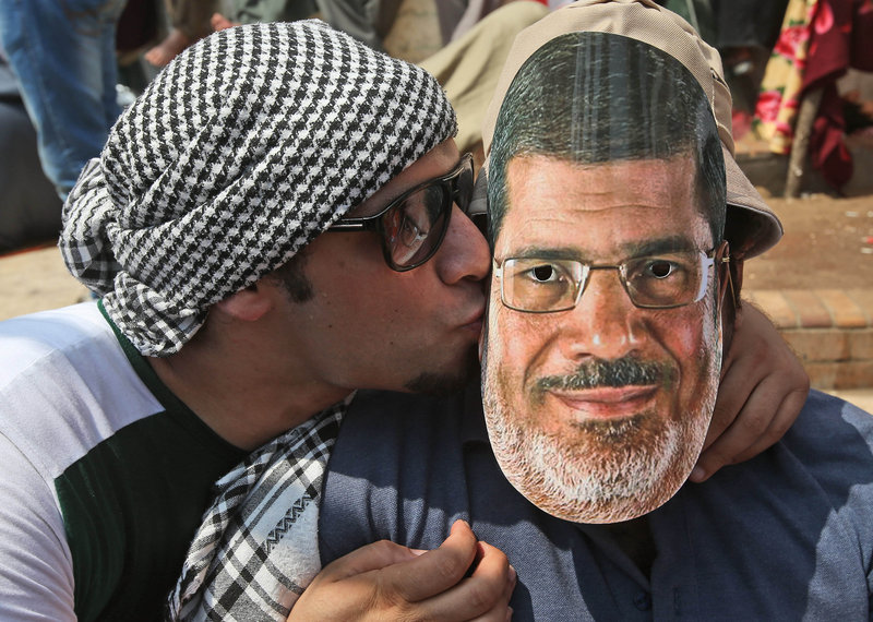 A supporter of Egypt’s ousted President Mohammed Morsi, left, kisses a mask depicting Morsi worn by a fellow demonstrator Friday in Cairo. At the same time, supporters of Egypt’s Muslim Brotherhood rallied in cities across Egypt.
