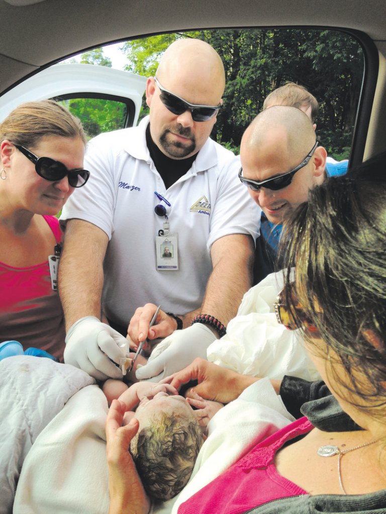Delta Ambulance paramedic Jeremy Manzer, center, checks on baby Michael, who was delivered in the back seat of a car in Fairfield this morning. The parents, Jill and Chris Demanski, of Jackman, were driving to Inland Hospital in Waterville but had to pull over into a stranger's driveway, where the baby was delivered at 7:35 a.m.