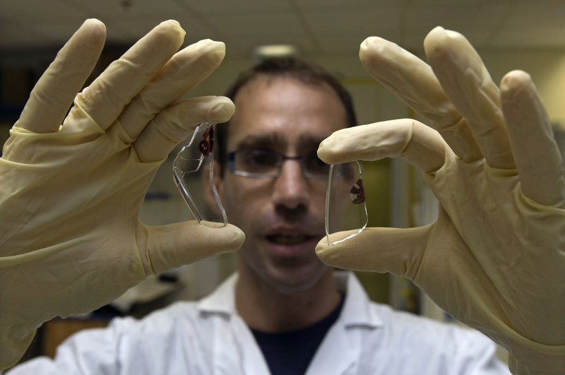 A scientist displays two DNA samples at a lab in Tel Aviv. Intensive DNA collection is taking place around the world, but relatively little debate is taking place over the ethical questions that are likely to arise.
