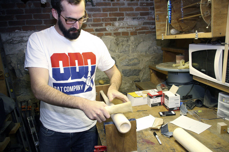Casey O’Donnell uses a cow femur to harden and smooth one of the wooden bats being made in Pittsfield, Mass.