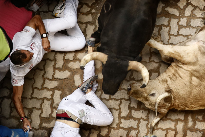 Revelers and bulls lie on the ground during the running of the bulls in Pamplona, Spain, on Saturday.
