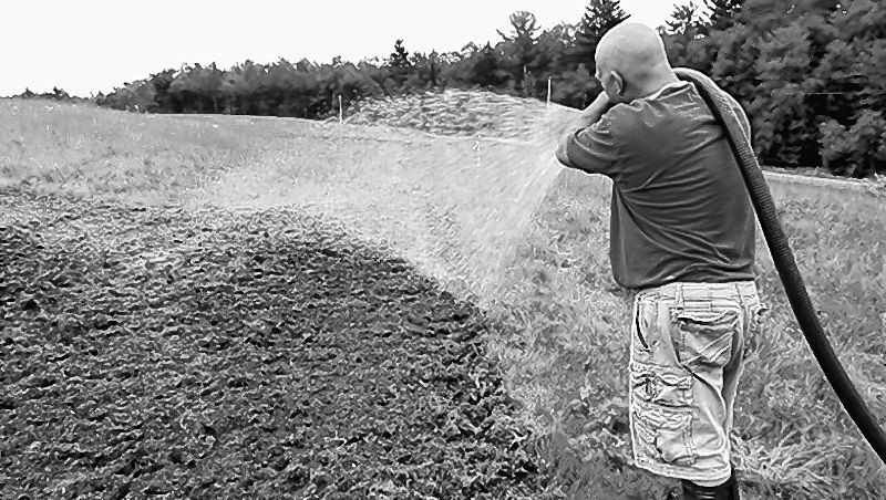 Norm Vigue of Central Maine Hydroseeding sprays a cover of wood fiber mulch, fertilizer and water onto the ground to protect newly planted wildflower seeds and help them grow at the Oakland transfer station.