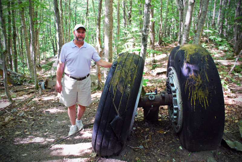 Matt Miller stands by the B-52’s tires, part of an enormous swath of debris resulting from the plane crash on Elephant Mountain more than 50 years ago.