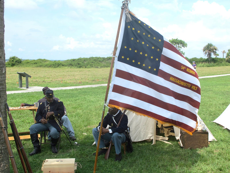 Walter Sanderson of Upper Marlboro, Md., left, and Louis Carter of Richmond, Va., re-enactors portraying members of the 54th Massachusetts Volunteer Infantry, sit in an encampment at Fort Moultrie on Sullivans Island, S.C., on Thursday, July 18, 2013. The re-enactors gathered to commemorate the 150th anniversary of the famed Civil War attack by the 54th Massachusetts Volunteer Infantry in a fight commemorated in the film "Glory." Prayers, a wreath-laying, candlelight and period music are planned to observe the attack on Battery Wagner that debunked the myth that black soldiers could not fight. (AP Photo/Bruce Smith)