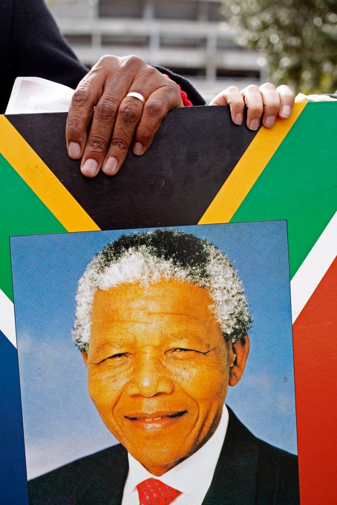 A placard depicting the face of former South African president Nelson Mandela is carried by people honoring his 95th birthday in Cape Town, South Africa, Thursday.