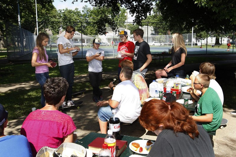 Gideon Maki, 20, second from left in background, reads a passage from Lamentations, in which Jeremiah talks about suffering, during a recent Skate Church service at the Skate Park in Woodland Park in Lexington, Ky.