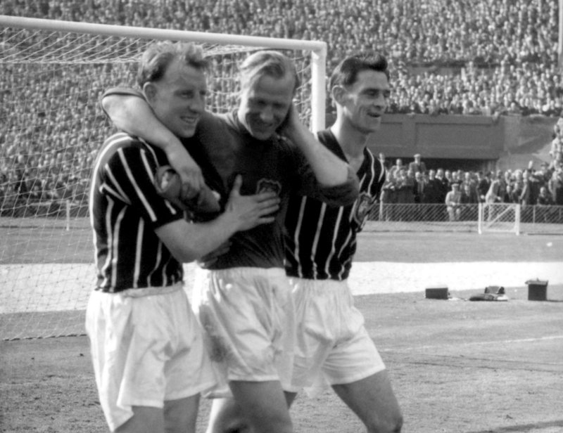 Manchester City’s Bert Trautmann, center, is assisted by unidentified players after he helped his team win the May 1956 FA Cup final, despite a broken neck.