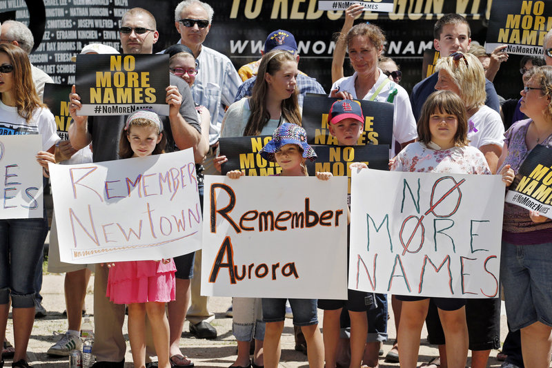 People hold signs as they gather for a remembrance rally for the Aurora theater shooting victims at Cherry Creek State Park in Aurora, Colo., on Friday. Saturday is the anniversary of the theater massacre where 12 people were killed and 70 wounded.