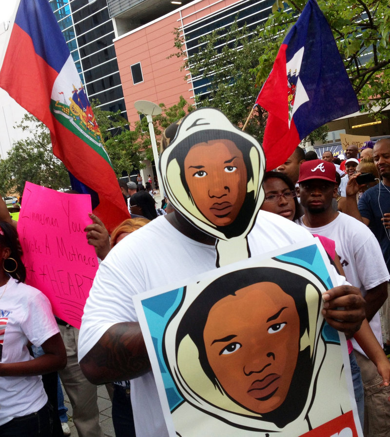 Aqua Etefia holds signs during a “Justice for Trayvon” rally in Miami on Saturday. The Rev. Al Sharpton’s National Action Network organized rallies nationwide to press for federal civil rights charges against George Zimmerman.