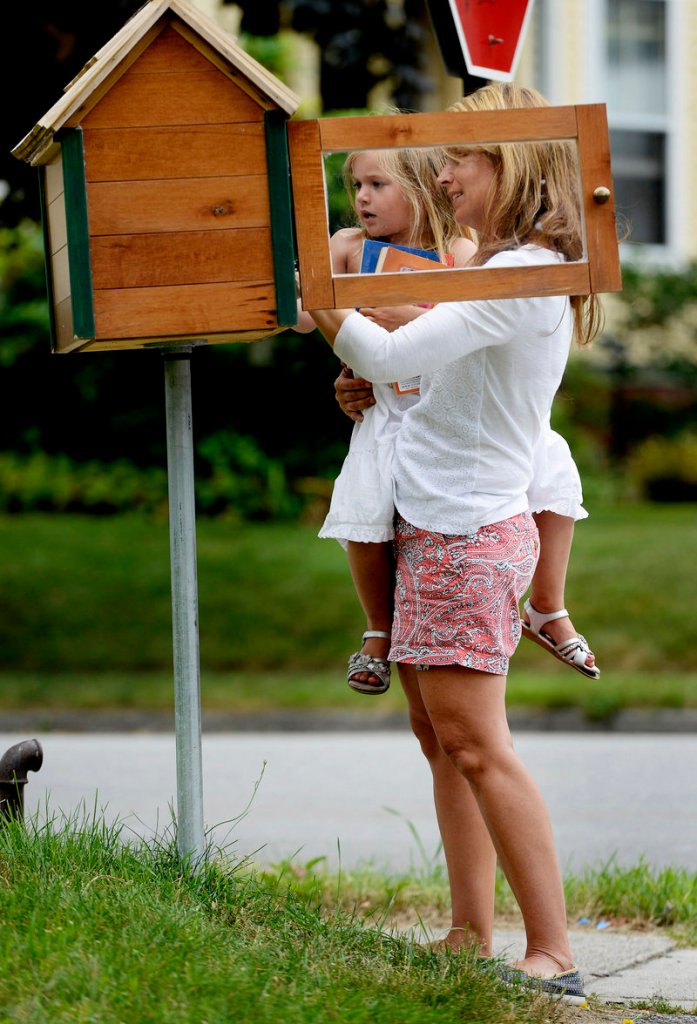 Kristin Jordan and her daughter Ruby, 3, look over the selection of books in their Little Free Library at their Portland home.