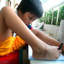 VIETNAMESE GIRL WITH NO ARMS WRITES WITH HER FOOT IN HO CHI MINH CITY.