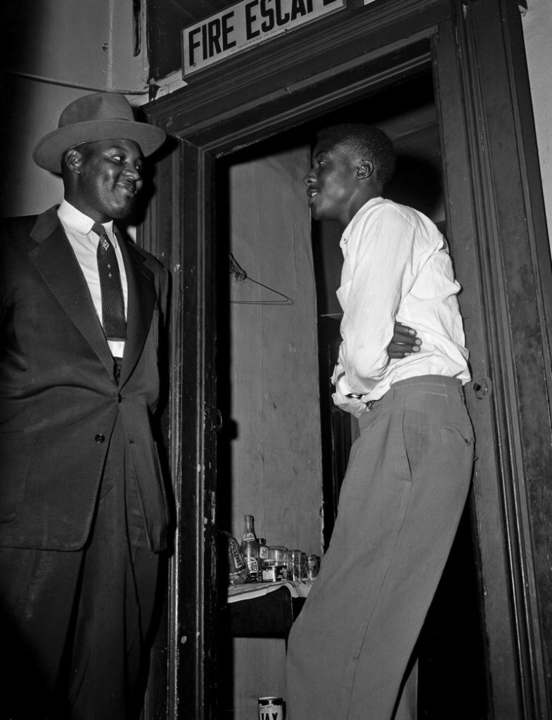 Willie Louis, then known as Willie Reed, right, a witness in the Emmett Till murder case in Mississippi, stands outside his apartment in Chicago, guarded by Detective Sherman Smith in 1955.