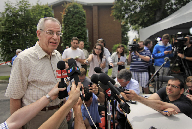 Ed Burkhardt, chairman of the Montreal, Maine & Atlantic Railway, is surrounded by media representatives after arriving in Lac-Megantic, Quebec, on July 10. Burkhardt, the head of the company whose oil-tanker train killed 47 people when it exploded in the small Quebec town, heard cries of “murderer” from furious town residents.