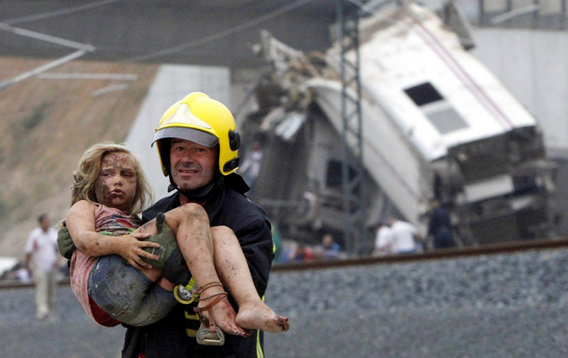 A firefighter carries an injured victim from the wreckage of a train crash near Santiago de Compostela in northwestern Spain. Witnesses said a fire, probably burning diesel fuel, engulfed passengers trapped in at least one of the rail cars.