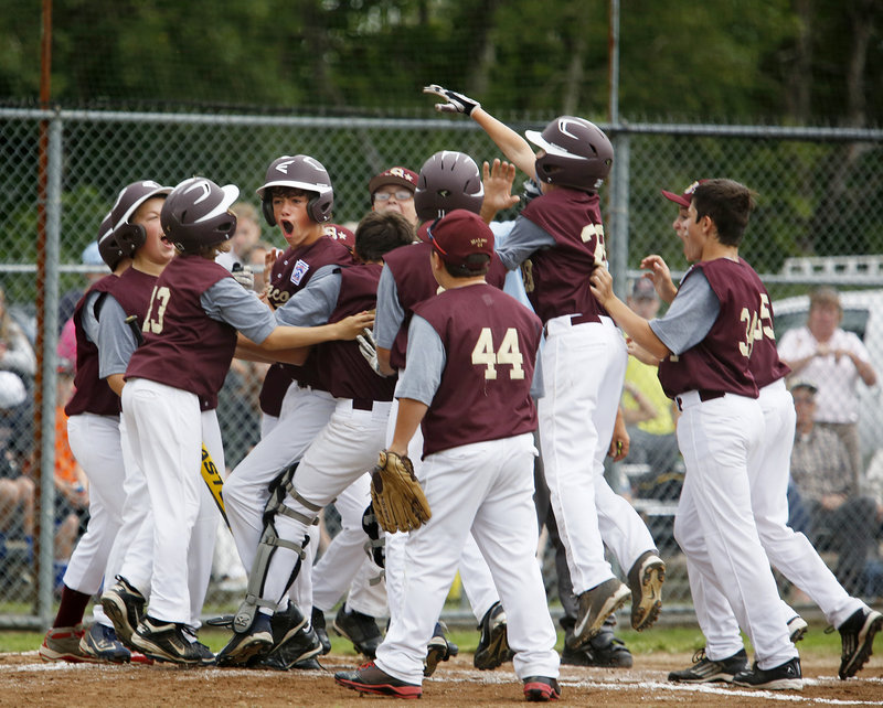 Michael Bourgault of Saco is mobbed by teammates after hitting a three-run homer in the second inning, breaking a tie on the way to a 12-4 win.