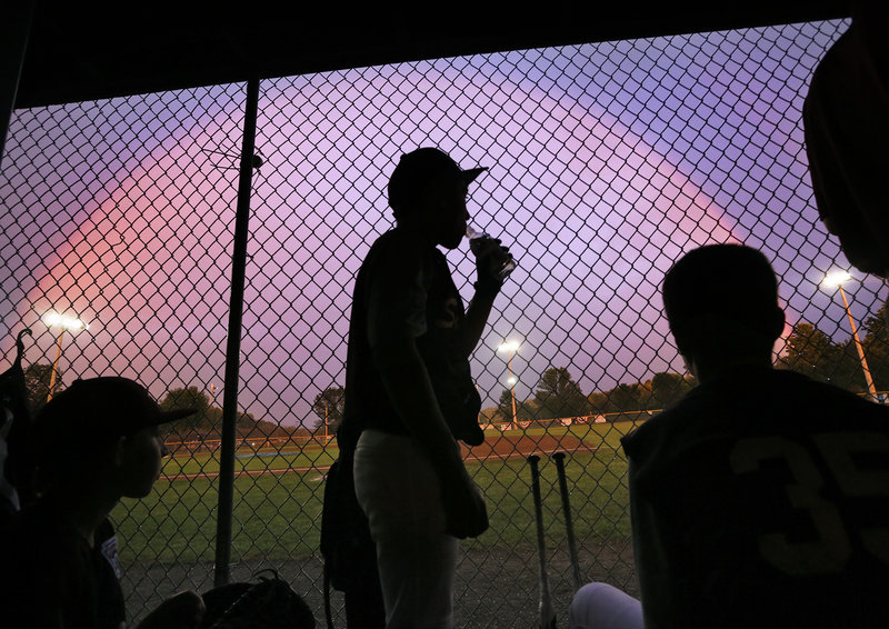 As rain delays the game Thursday night, the Saco Little League baseball players get a chance to admire a colorful sky from their dugout in Augusta during the state-tournament game against Bayside of Portland.