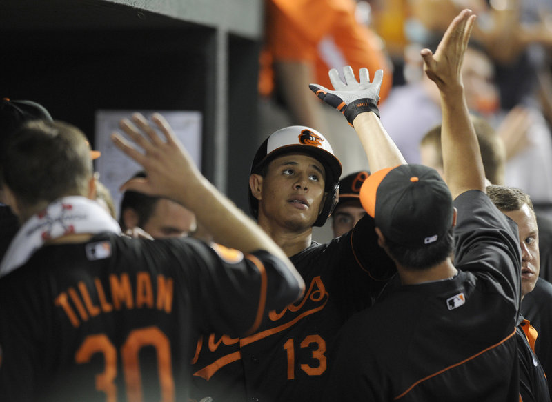 Manny Machado gets a big welcome from the dugout, including winning pitcher Chris Tillman, after homering for Baltimore in the seventh inning Friday night.
