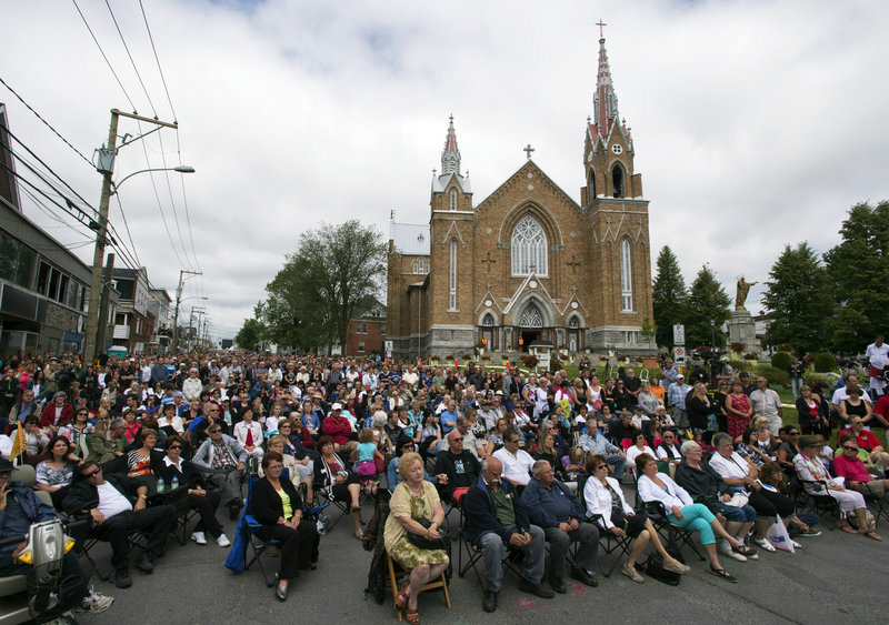 An overflow crowd watches a giant screen outside the Ste-Agnes church during a memorial service on Saturday.