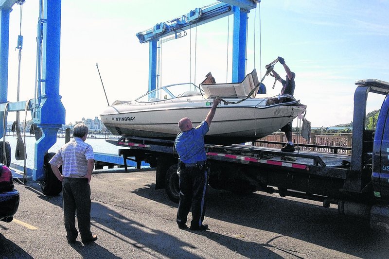 Police load a 21-foot powerboat onto a trailer in Piermont, N.Y., Saturday, after it struck a barge Friday night.